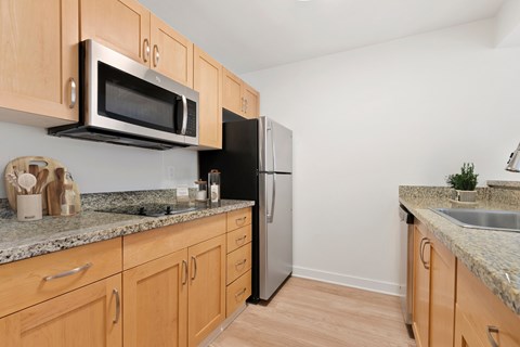A kitchen with wooden cabinets and a black refrigerator.