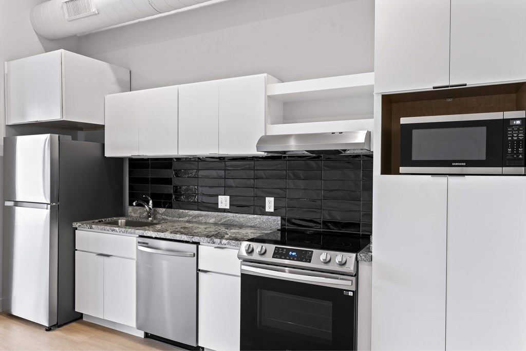 A modern kitchen with white cabinets and black appliances. at Brickside Heights, Millcreek, 84106