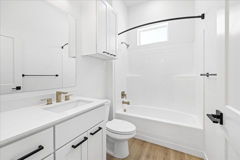 A white bathroom with a toilet, sink, and bathtub.at Alante Homes at Spring Run, Idaho, 83607