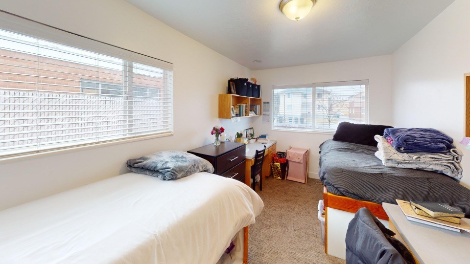 A bedroom with two beds and a desk.
