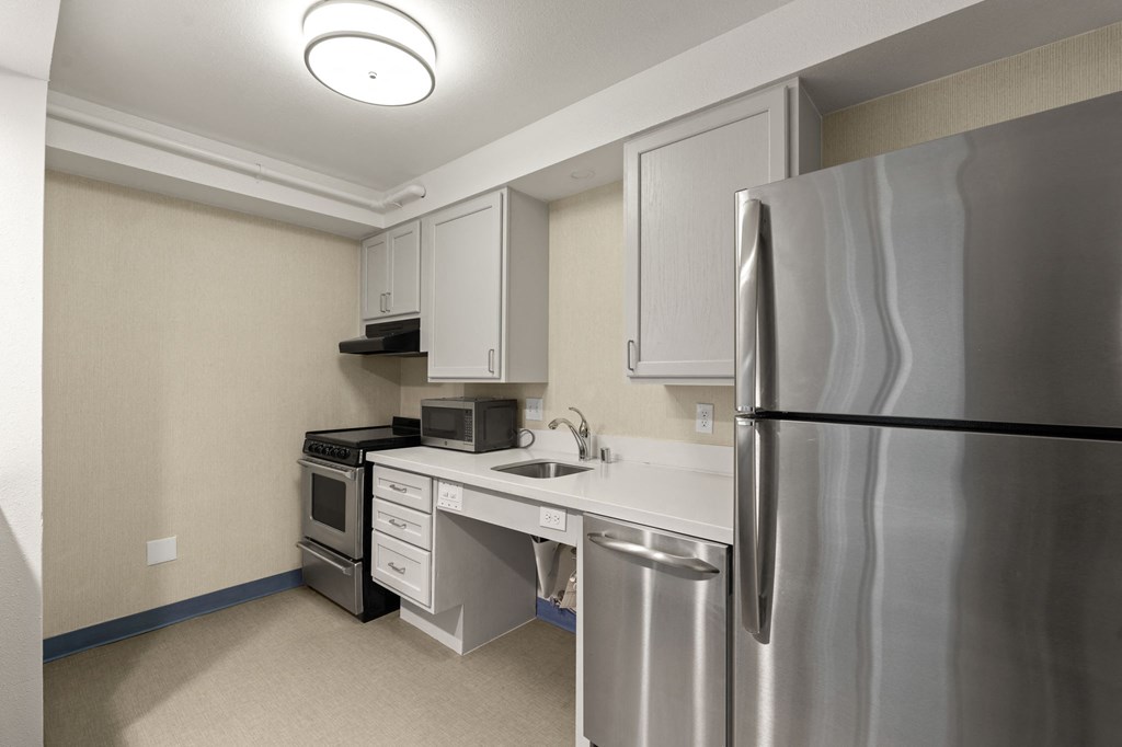 A kitchen with a stainless steel refrigerator, microwave, oven, sink, and dishwasher at AVIA Lofts on Parkway Apartments, Vancouver, Washington