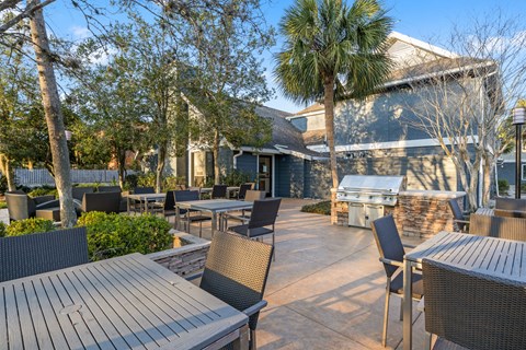 a patio with tables and chairs and a grill at AVIA Lofts on Liberty Ridge Apartments, Jacksonville 32256