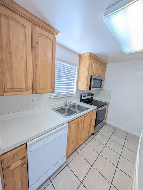 A kitchen with wooden cabinets and a white dishwasher.