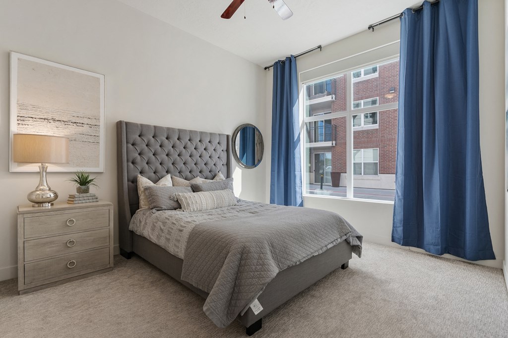 a bedroom with a bed and a window with blue curtains at 200 City View, Provo, UT