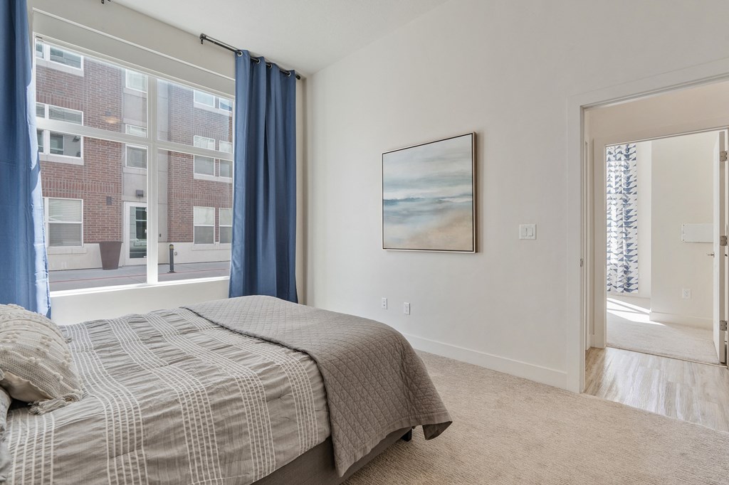 a bedroom with a bed and a large window with blue curtains at 200 City View, Utah