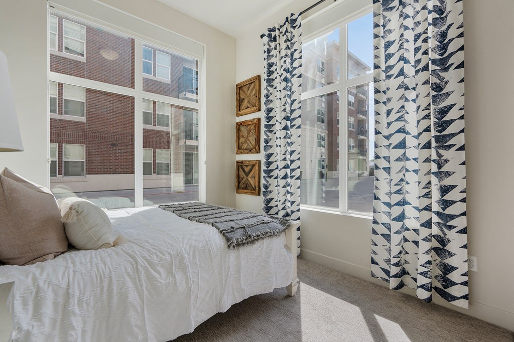 a bedroom with a bed and a window with blue and white curtains at 200 City View, Provo, Utah