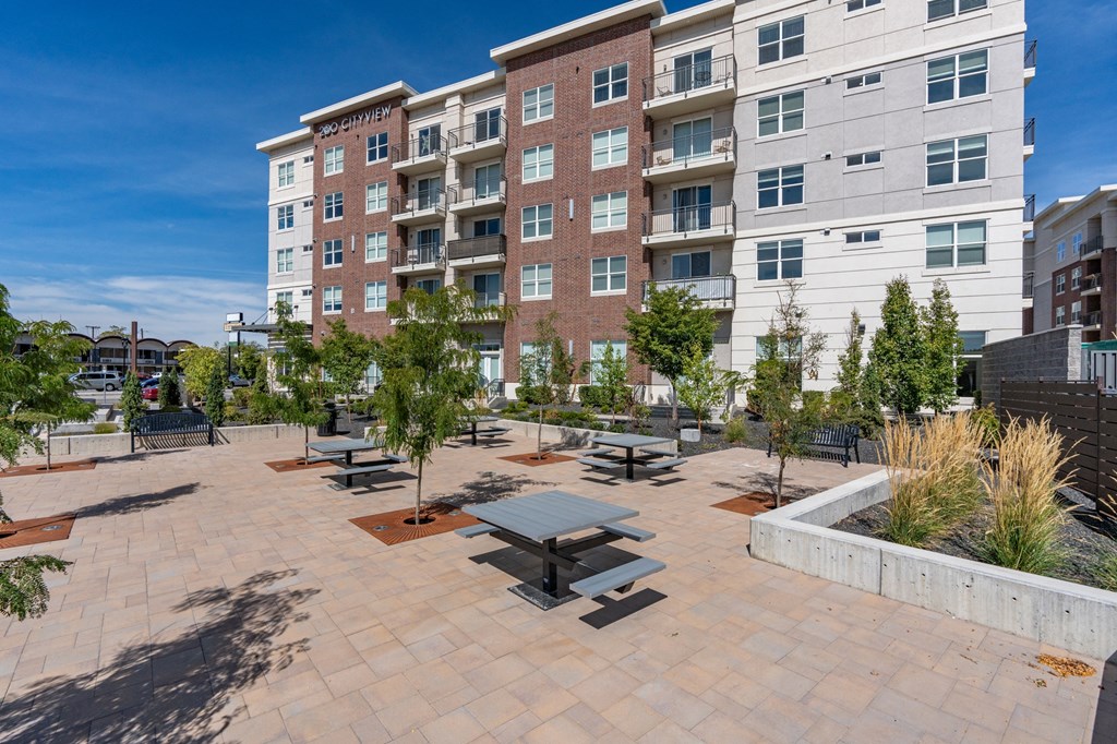 an outdoor patio with benches and trees in front of an apartment building at 200 City View, Provo, Utah