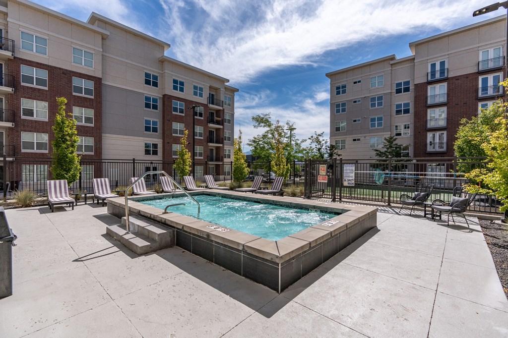 our apartments have a resort style pool with lounge chairs and an apartment building at 200 City View, Provo, Utah