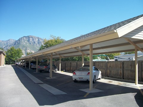 A long covered parking lot with cars parked in it.