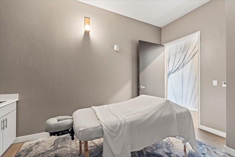 A room with a bed covered in a white sheet and a small ottoman.