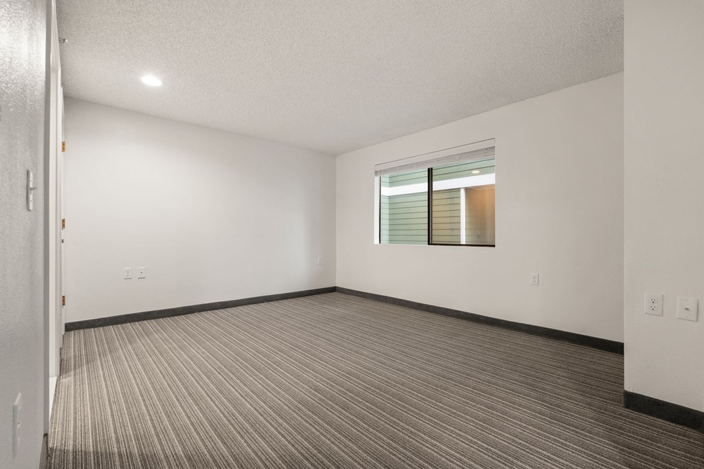 A room with a carpeted floor and a window with blinds. at AVIA Lofts on Parkway Apartments, Vancouver, 98662