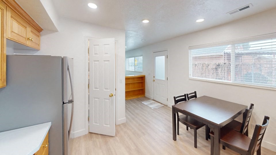 A kitchen with a refrigerator, table and chairs.