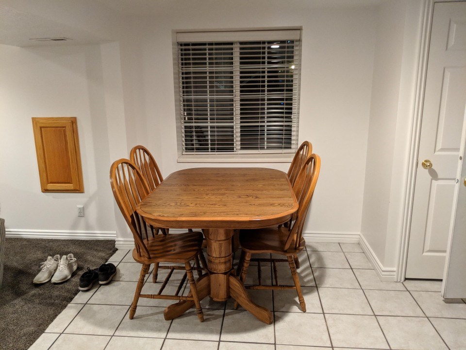 A wooden table and chairs are in a room with a window.