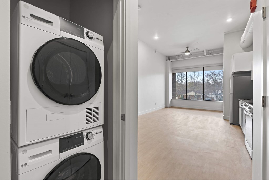 A modern laundry room with a washer and dryer stacked on top of each other. at Brickside Heights, Utah