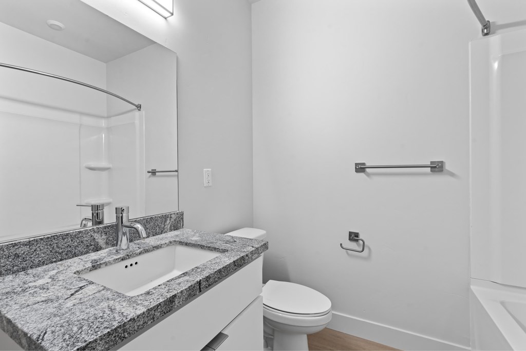 A bathroom with a sink, toilet, and a shower. at Brickside Heights, Millcreek, UT