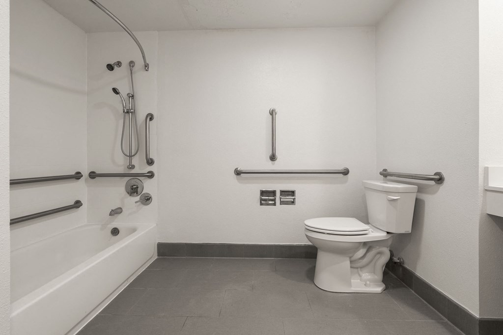 A white toilet in a bathroom with a shower head and hand held shower at AVIA Lofts on Parkway Apartments, Vancouver, WA, 98662