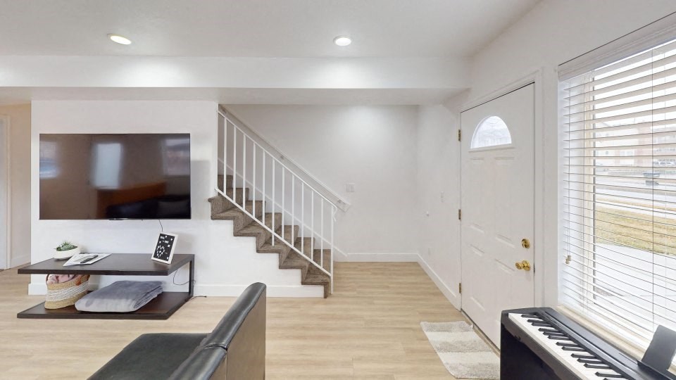 A living room with a piano and a staircase.