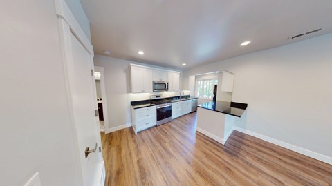 A kitchen with white cabinets and a wooden floor.