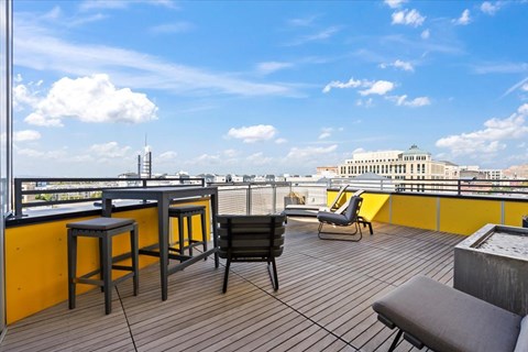 A balcony with a table and chairs overlooking a cityscape.