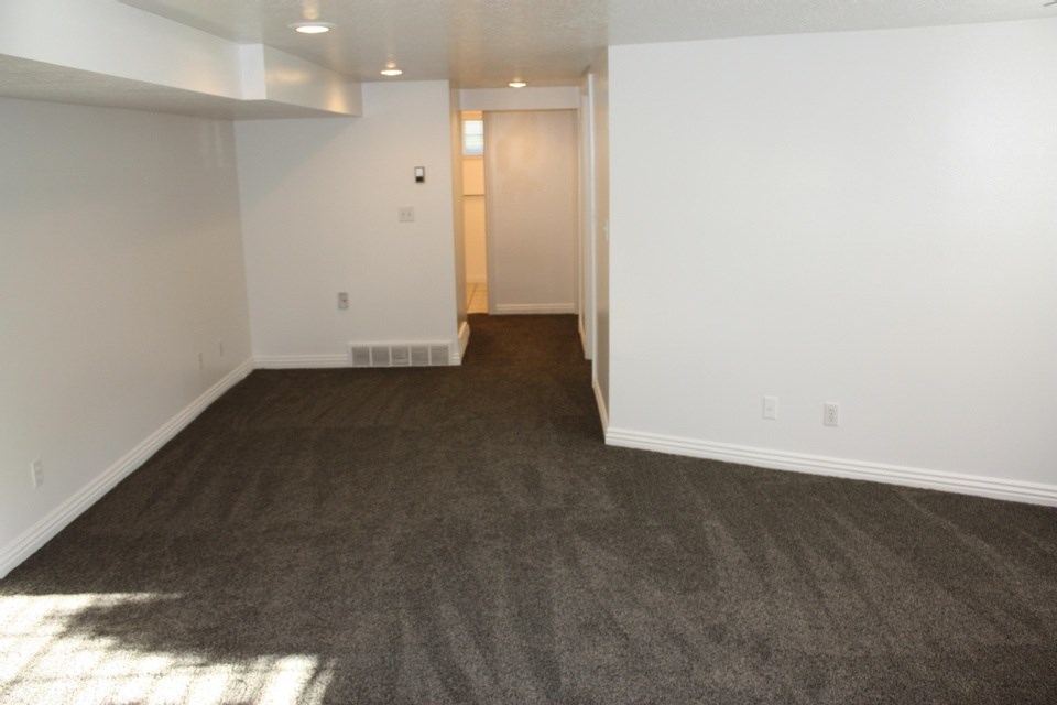 A room with a carpeted floor and a door in the distance.