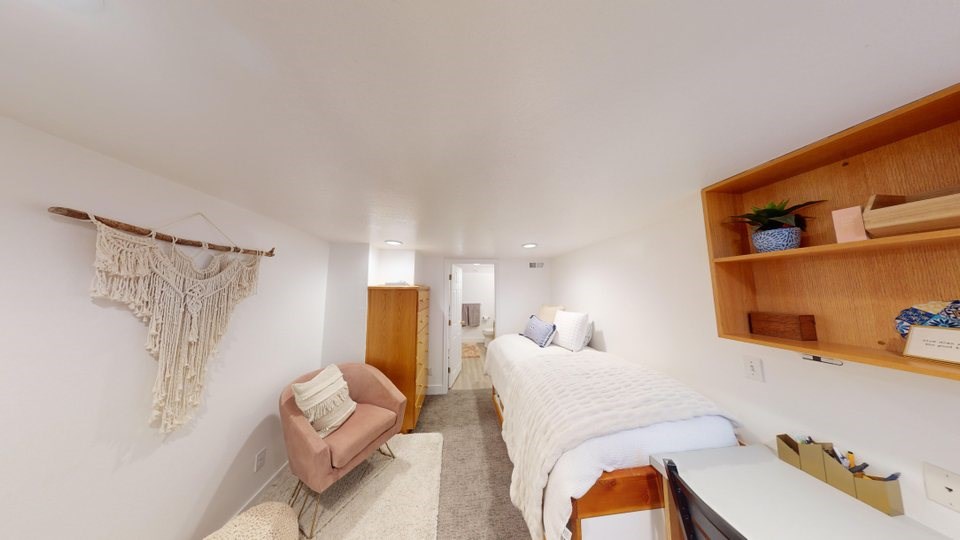 A bedroom with a bed, chair, and shelf.