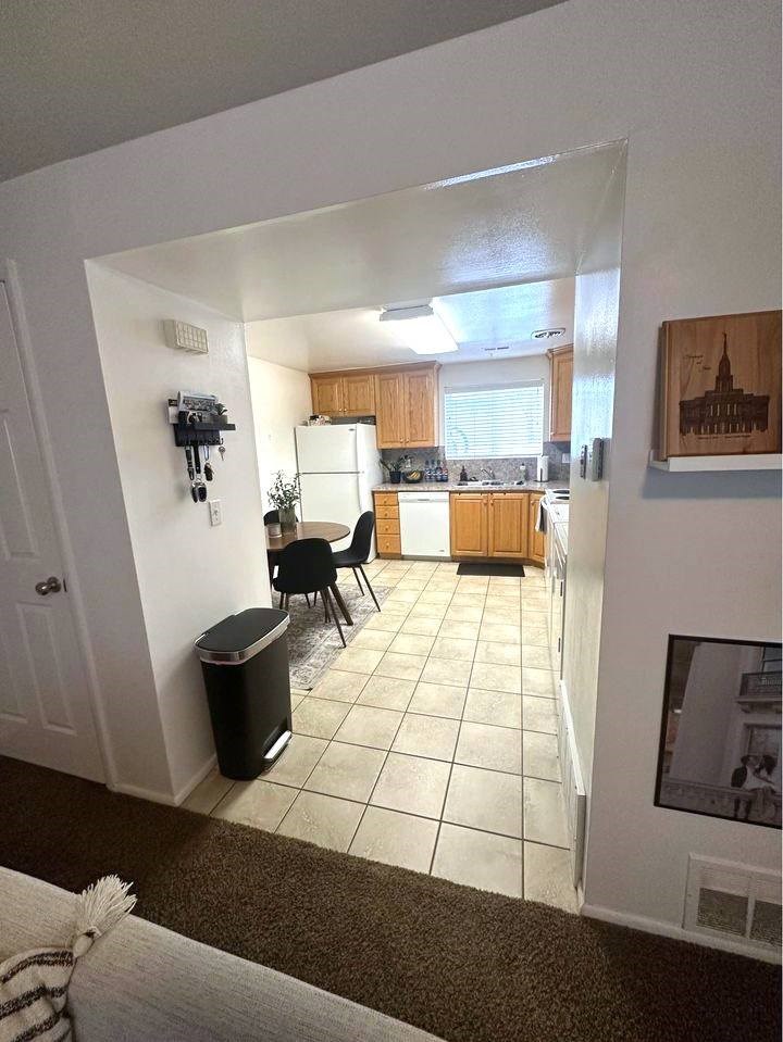 A kitchen with a dining table and chairs is visible from the living room.
