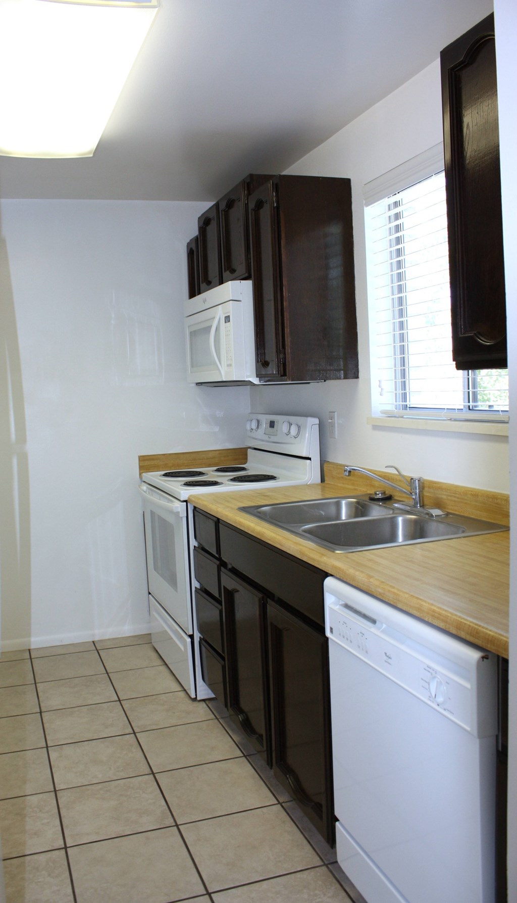A small kitchen with a white dishwasher and a white microwave above the stove.