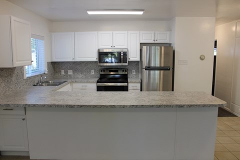 A kitchen with white cabinets and a granite countertop.