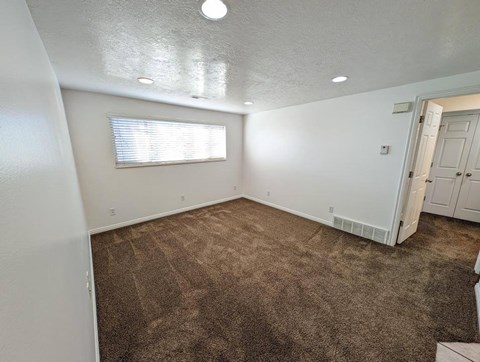 A room with a carpeted floor and a window with blinds.