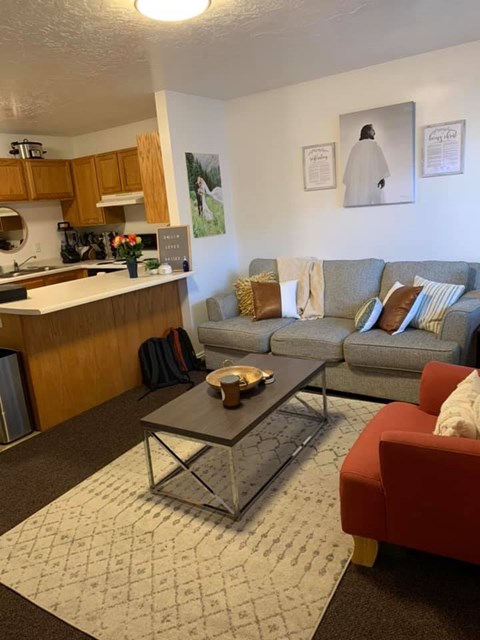 A living room with a grey couch and a red chair.
