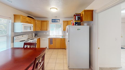 A kitchen with a white refrigerator and wooden cabinets.
