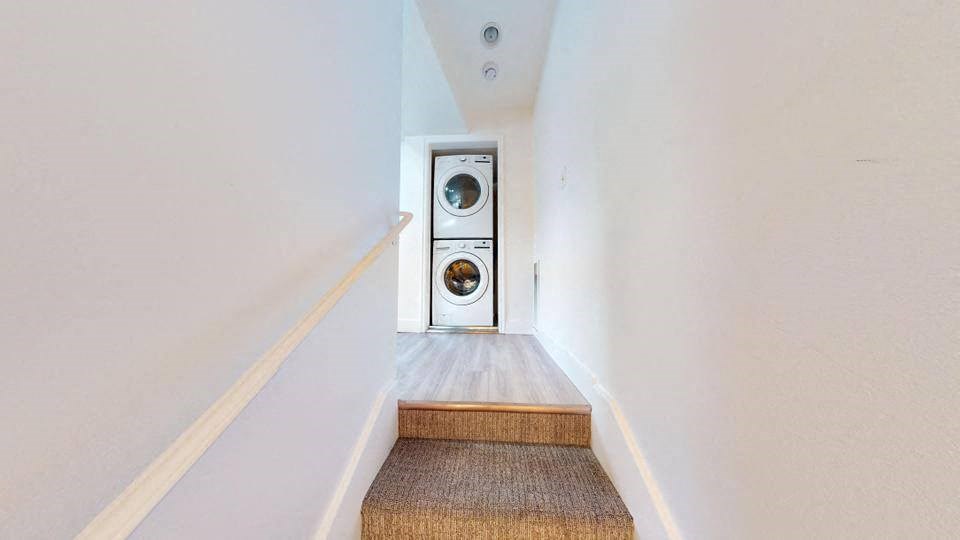 A stairway with a white wall and a wood handrail.