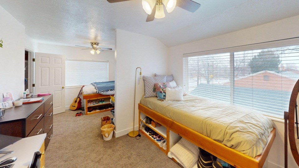 A bedroom with a bed, desk, and guitar.