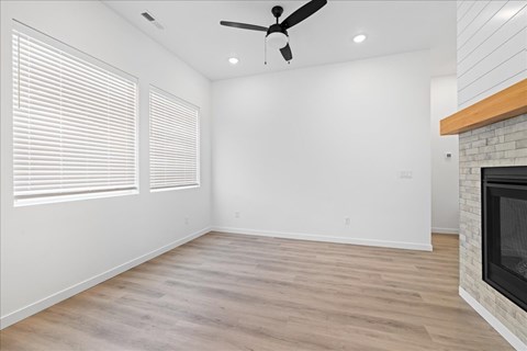 A room with a fireplace and a ceiling fan.at Alante Homes at Spring Run, Caldwell, 83607