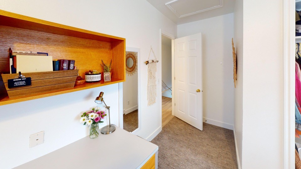 A small room with a wooden shelf and a white door.