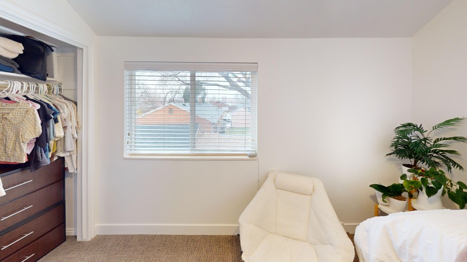 A white chair sits in a room with a window and a plant.