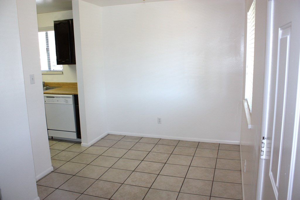 A white room with a tiled floor and a door on the right.