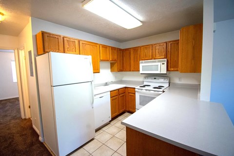 A white refrigerator is in a kitchen with brown cabinets.