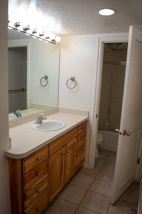 A bathroom with a sink, mirror, and lighting fixture.