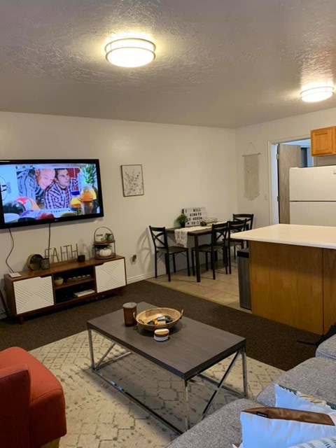 A living room with a television on the wall and a dining table with chairs.
