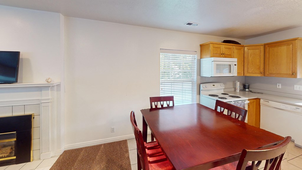 A kitchen with a table and chairs in front of a fireplace.
