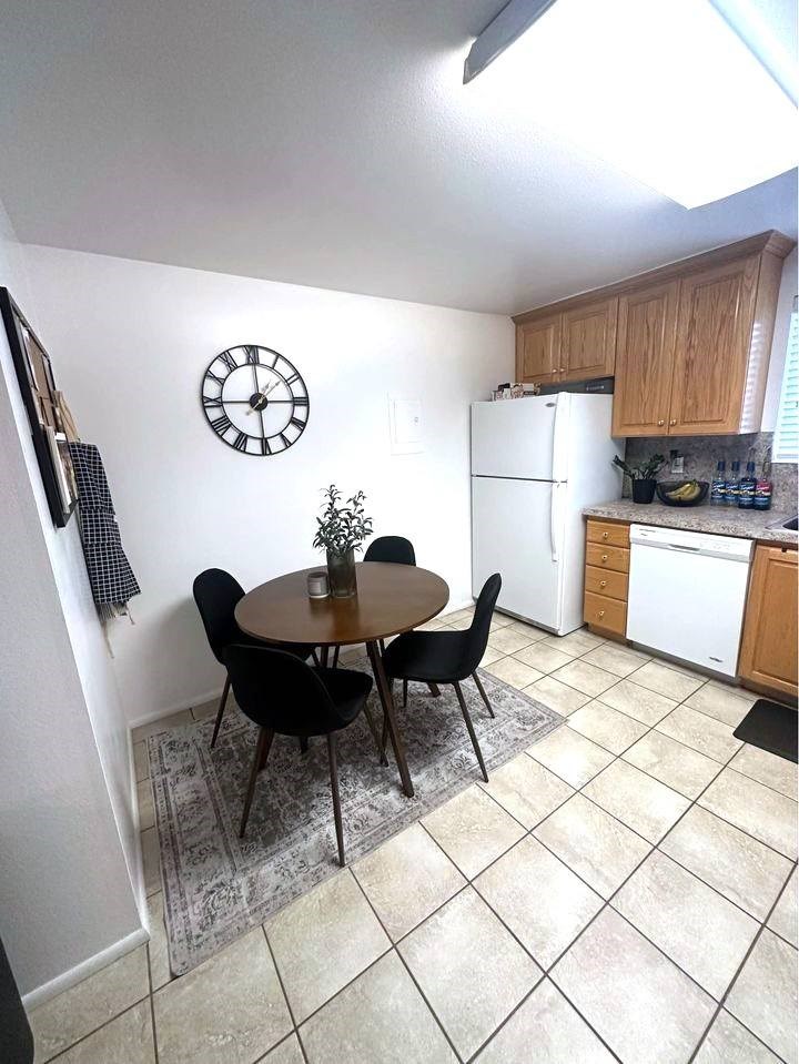 A kitchen with a table and chairs and a clock on the wall.