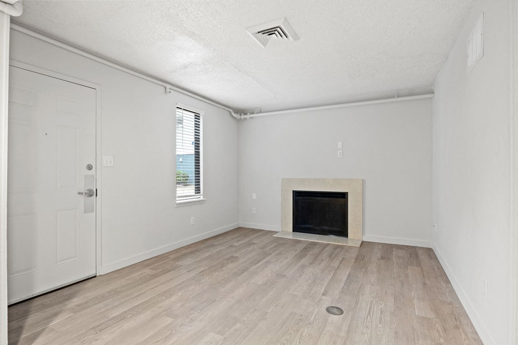an empty living room with a fireplace and wooden floors