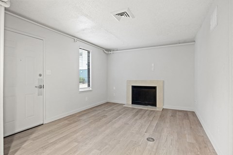 an empty living room with a fireplace and wooden floors at AVIA Lofts on Liberty Ridge Apartments, Jacksonville, FL