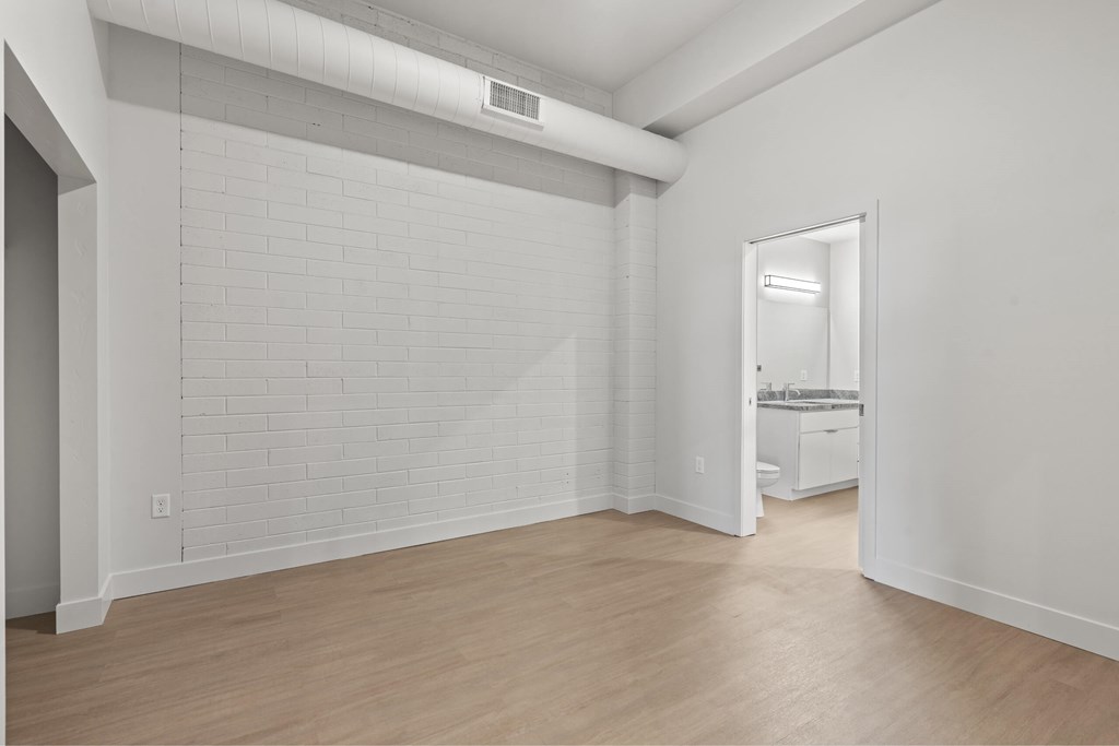 A white room with a brick wall and wooden floor. at Brickside Heights, Millcreek, Utah