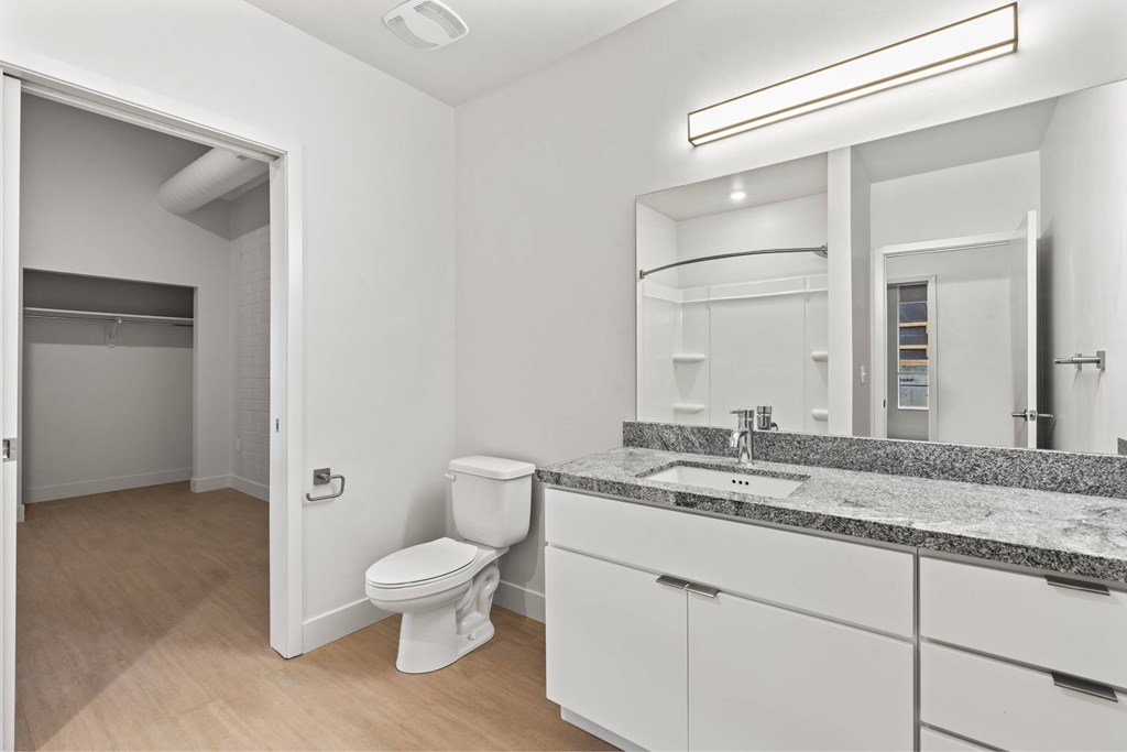 A bathroom with a toilet, sink, and mirror. at Brickside Heights, Millcreek, UT, 84106