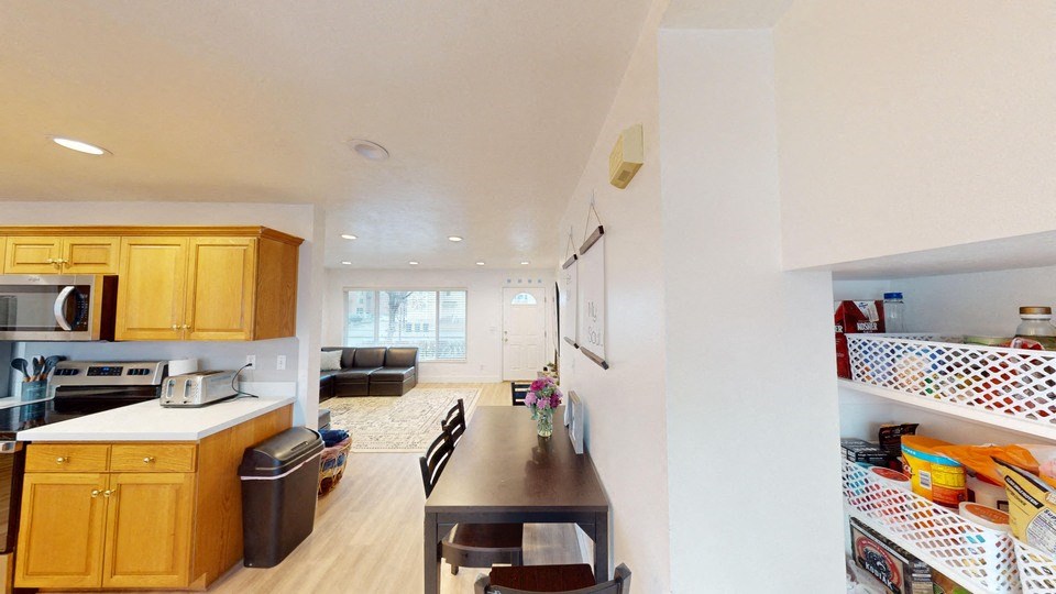 A kitchen with wooden cabinets and a black trash can.