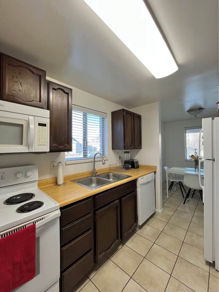 A kitchen with white appliances and brown cabinets.