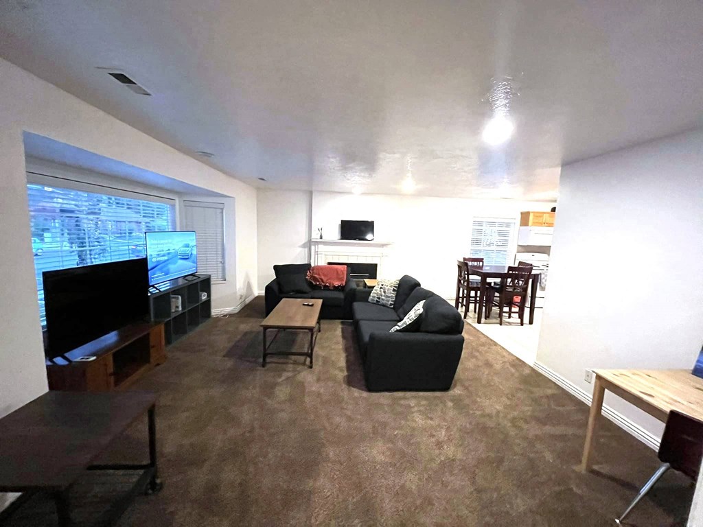 A living room with a black couch, a television, and a wooden coffee table.