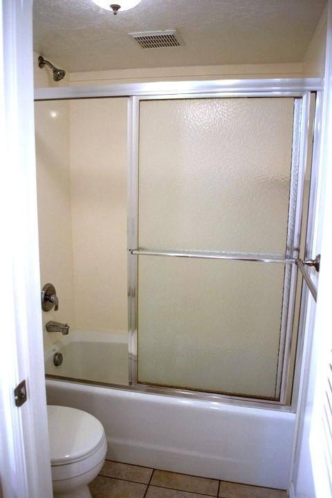 A white bathroom with a toilet and a walk in shower.